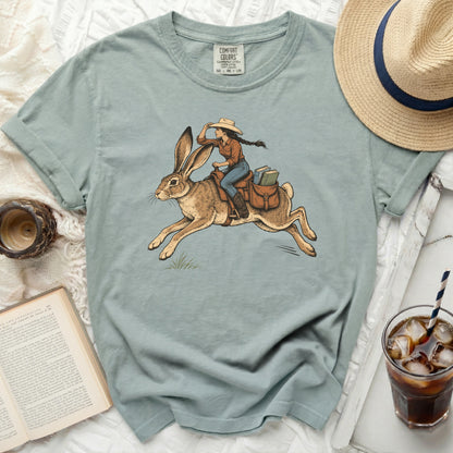 Girl riding a rabbit with books in saddlebags, on a comfort colors t-shirt.