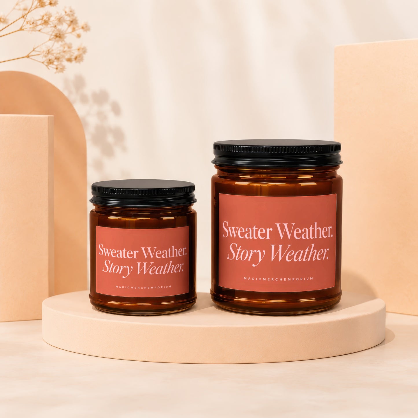 Two amber glass candles with black lids, one larger than the other.