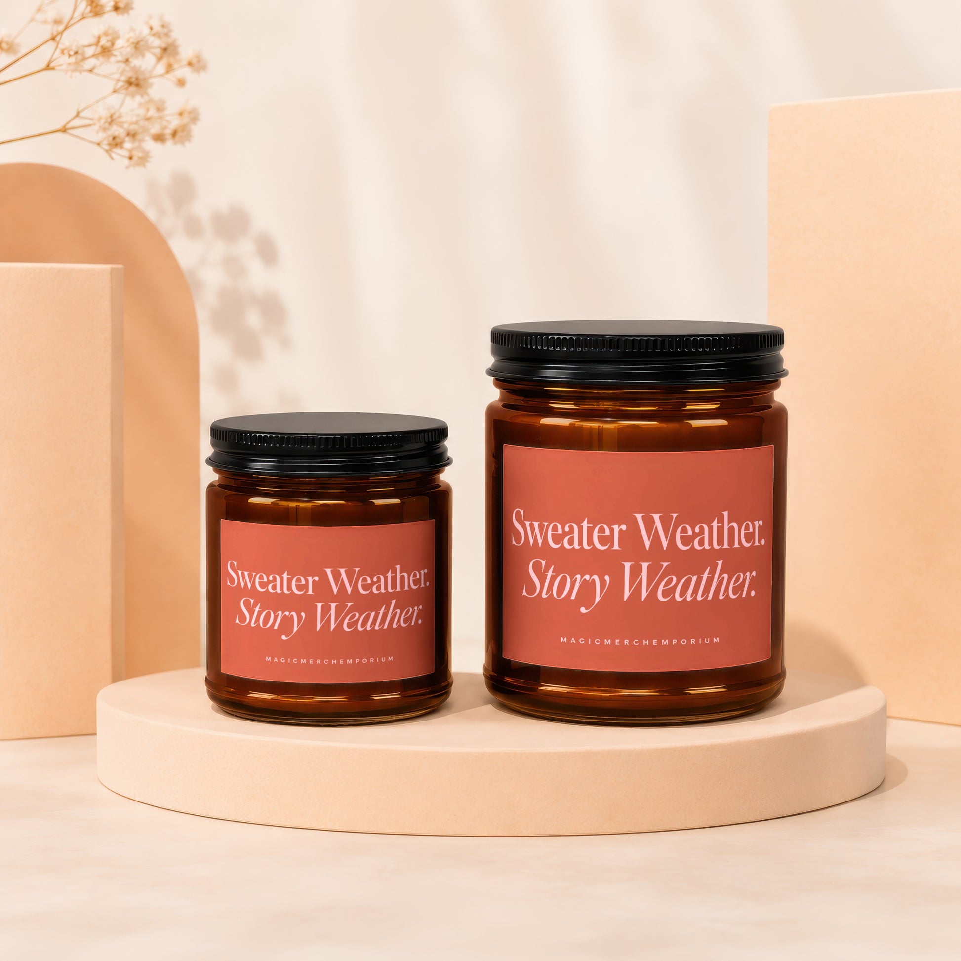 Two amber glass candles with black lids, one larger than the other.