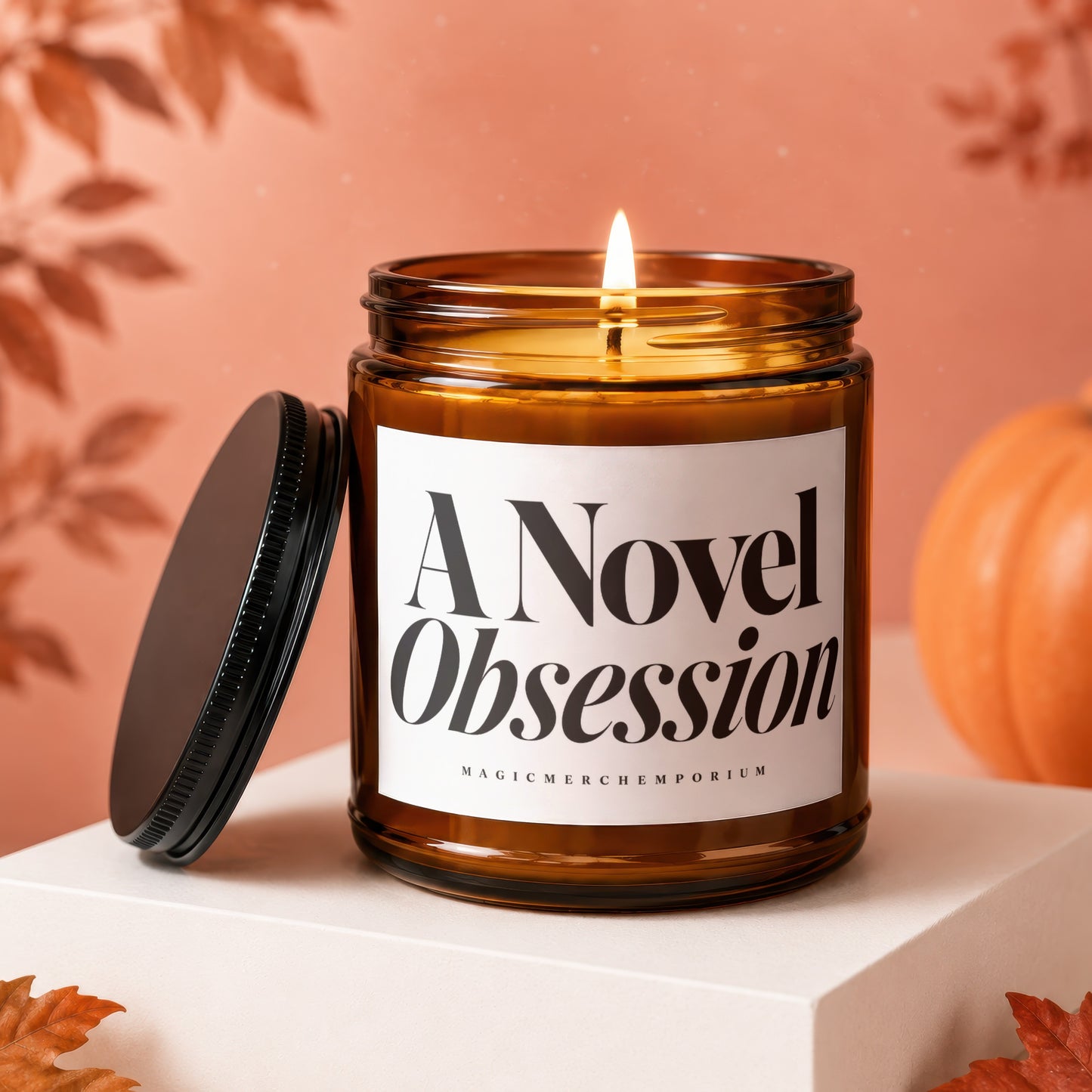 Amber jar candle with burning wick, lid off, label reads "A Novel Obsession"