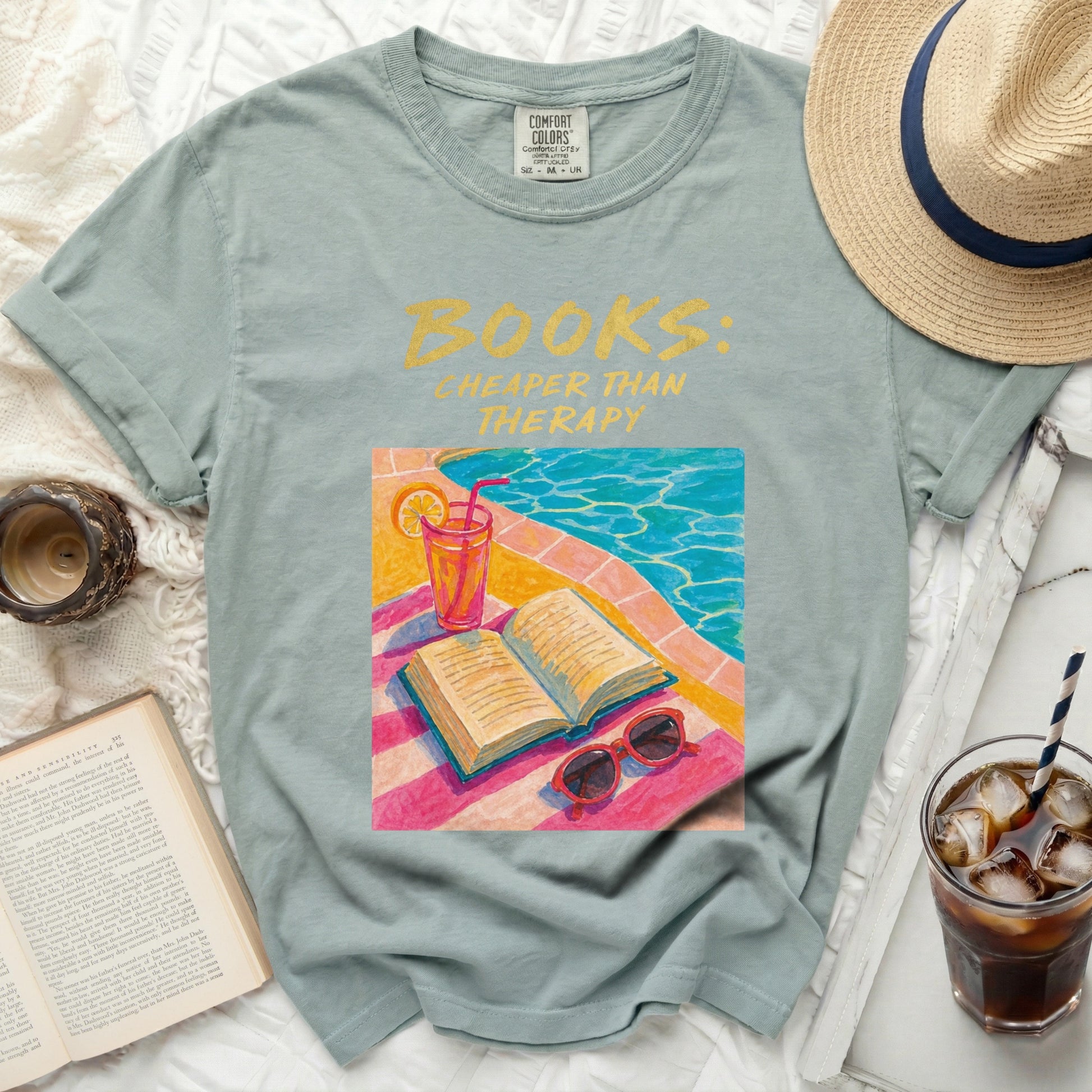 Light blue t-shirt with "BOOKS: CHEAPER THAN THERAPY" text and poolside book graphic.