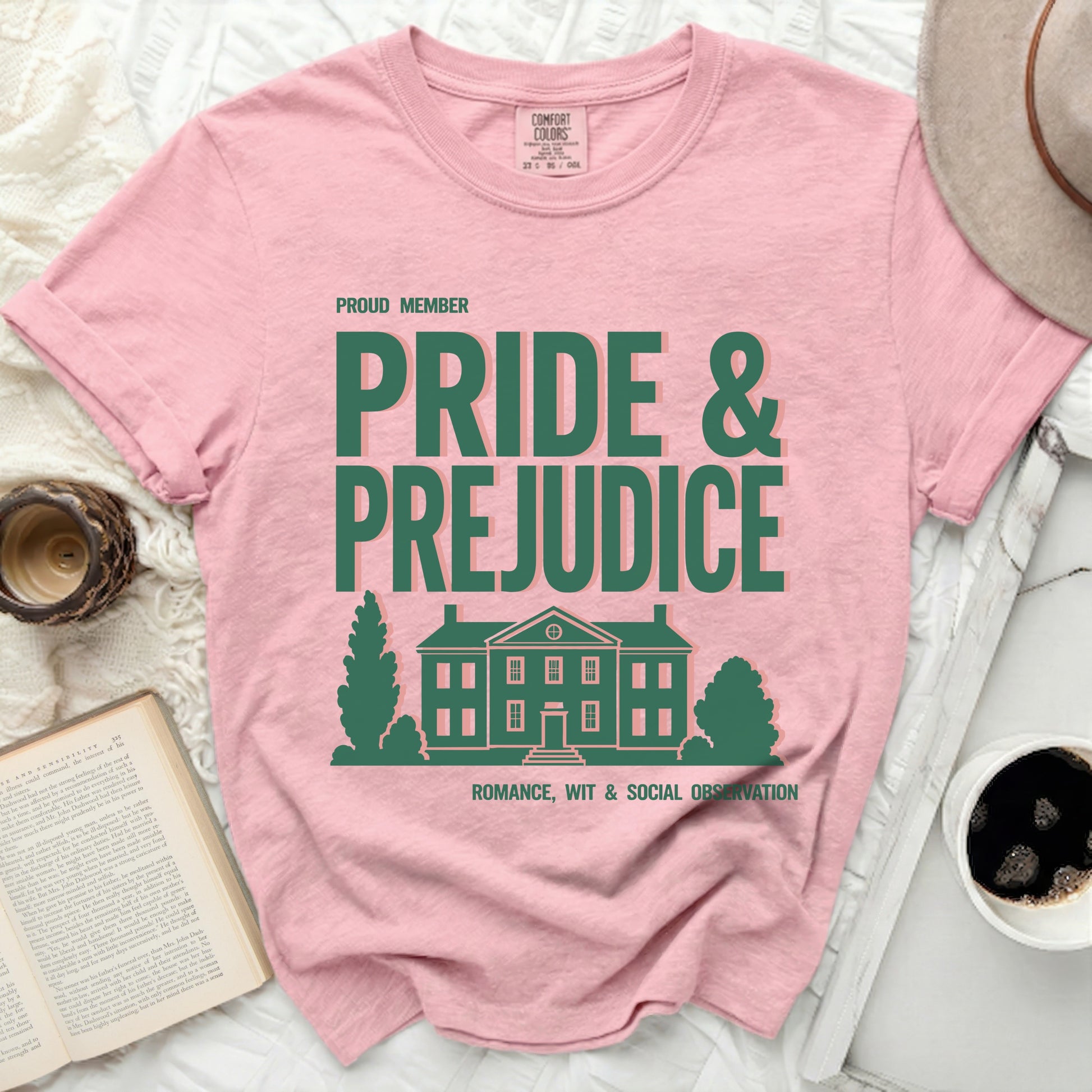 Pink shirt with "Pride & Prejudice" text and house graphic.