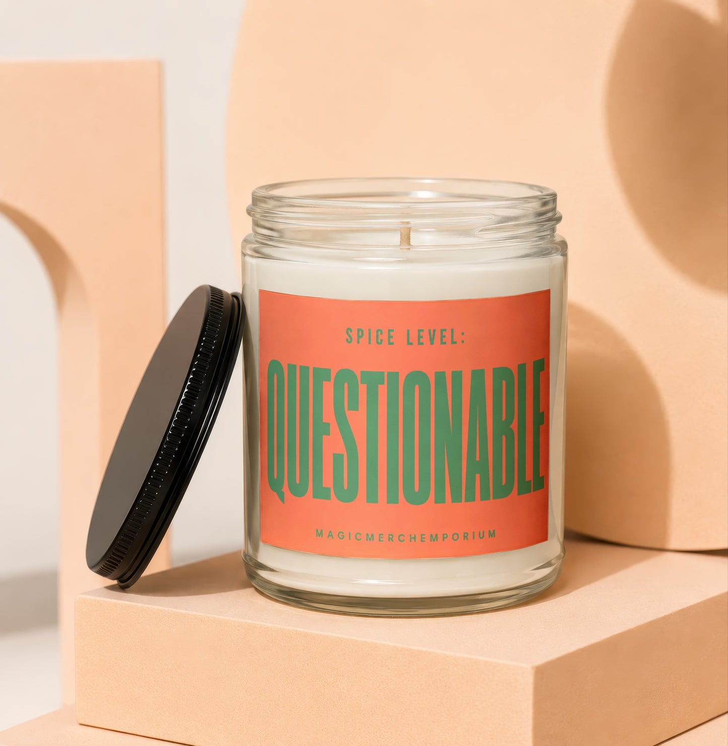 Glass candle with orange label reading "SPICE LEVEL: QUESTIONABLE" and "MAGICMERCH...".