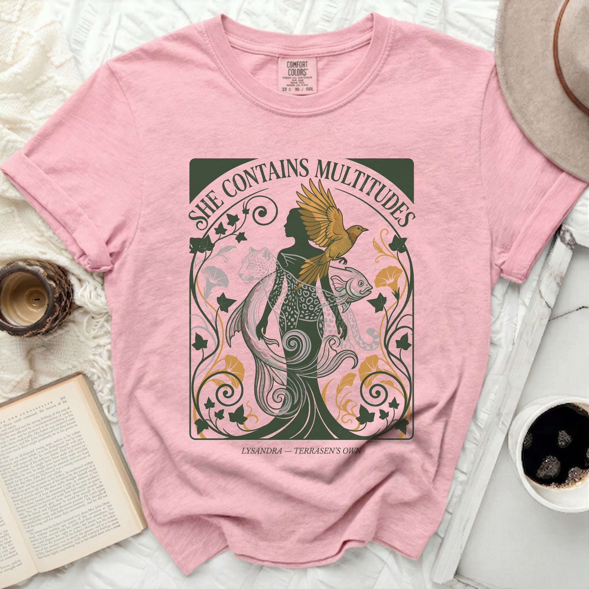 Pink t-shirt with "She Contains Multitudes" and mythological art.