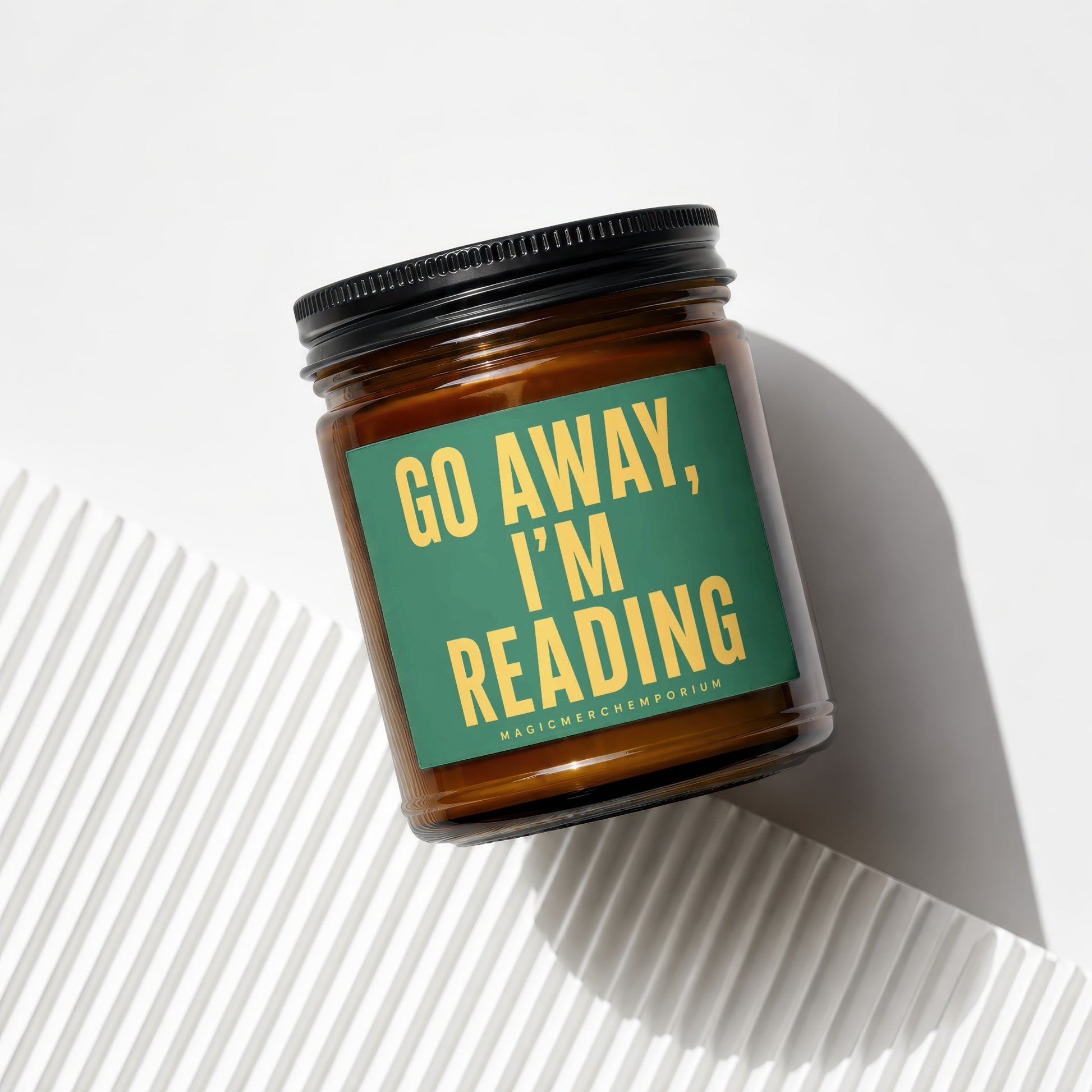 Brown glass candle with green label reading "Go Away, I'm Reading".