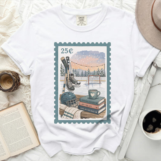 White t-shirt with stamp graphic of hockey scene, mug, and books.