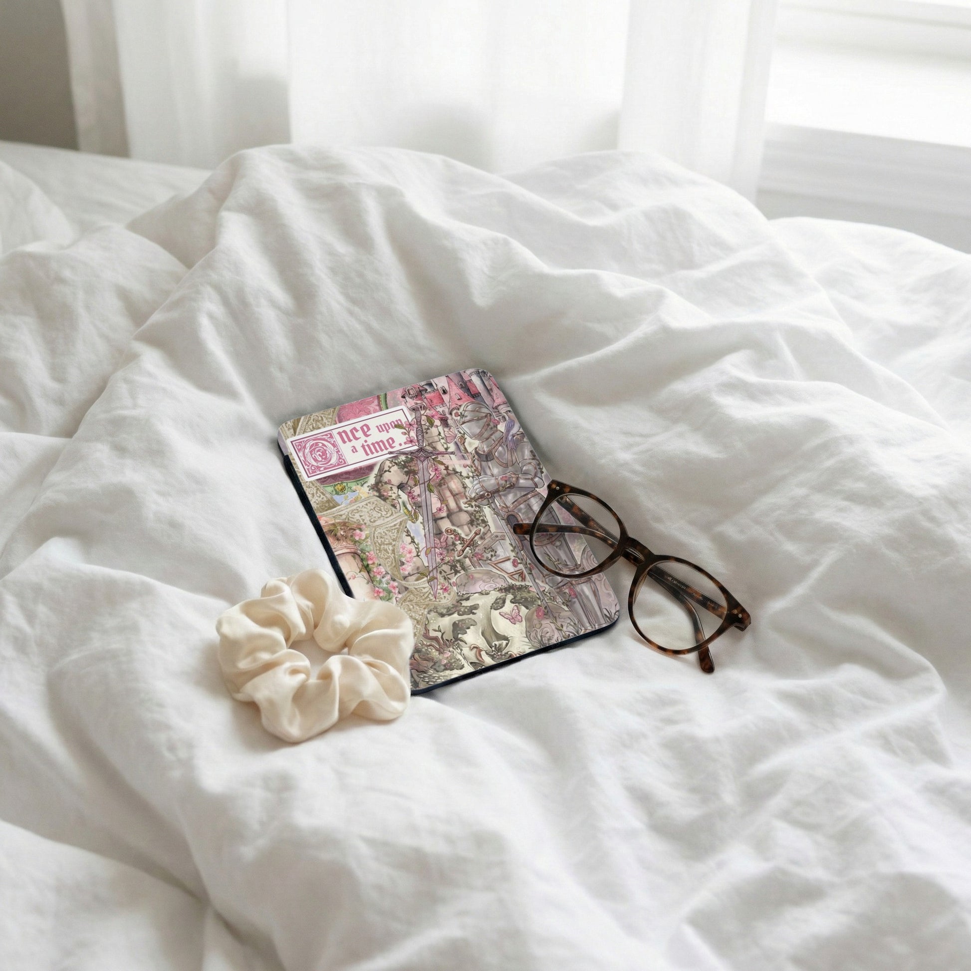 Journal with "Once upon a time" text, glasses, and scrunchie on rumpled white sheets.
