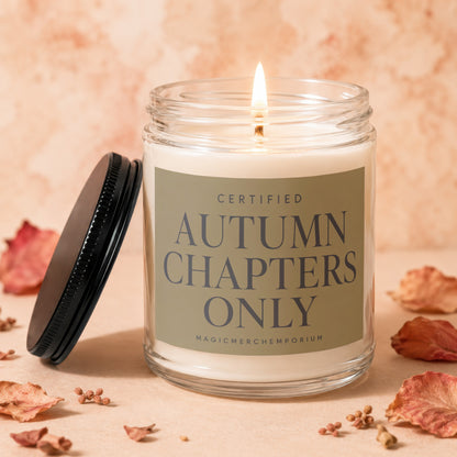 Lit glass jar candle with "Certified Autumn Chapters Only" label and black lid.