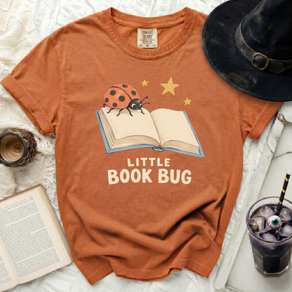Orange t-shirt with "Little Book Bug" graphic featuring a ladybug on a book.