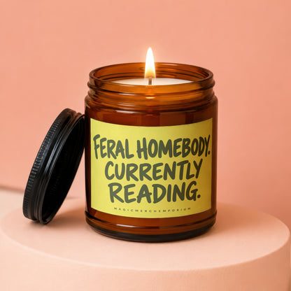 Brown glass candle with "Feral Homebody Currently Reading" on yellow label.