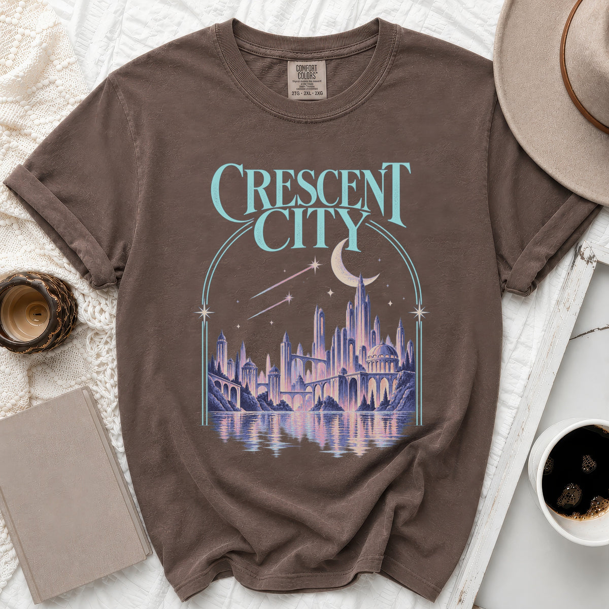 Brown t-shirt with "Crescent City" text and a fantastical city illustration.