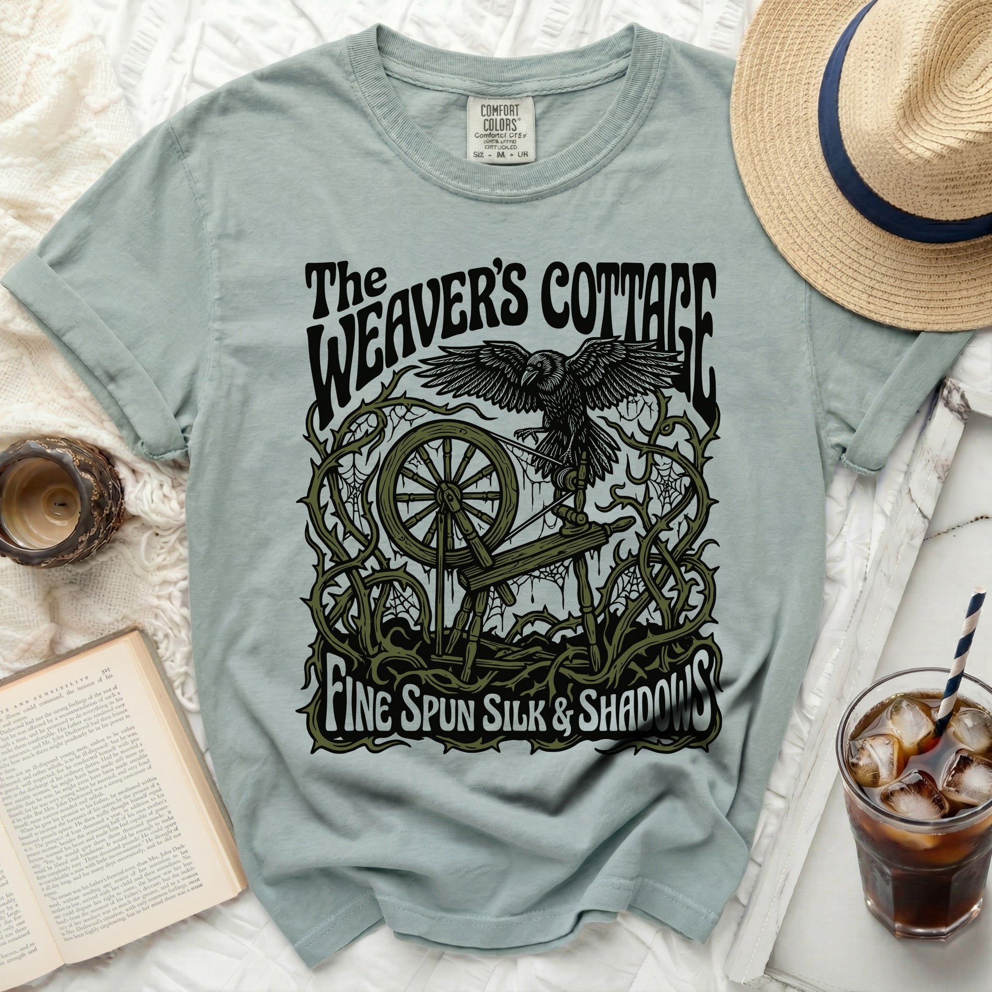 Light blue t-shirt with "The Weaver's Cottage Fine Spun Silk & Shadows" text and graphic.