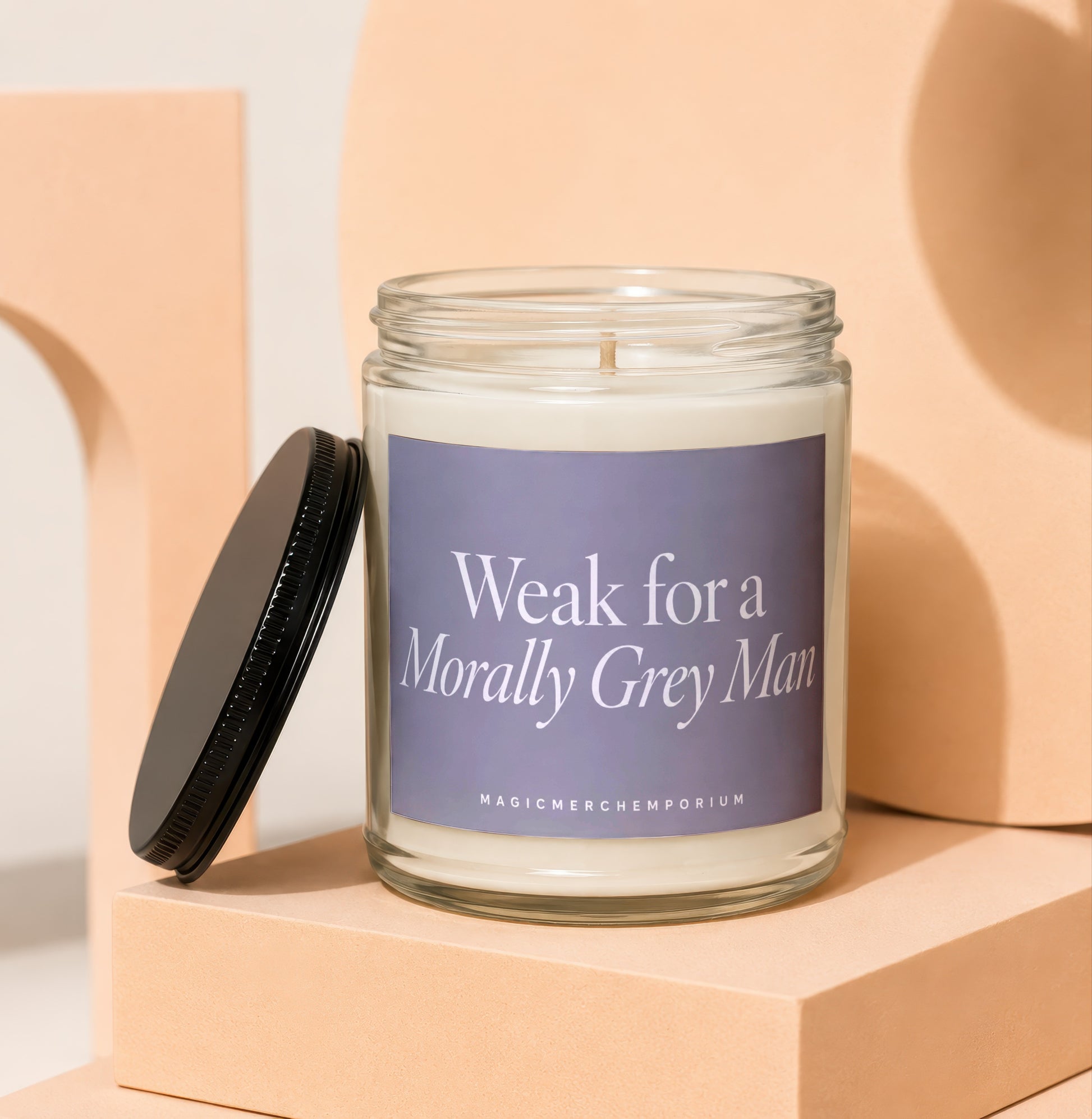 Glass candle with a black lid, featuring text "Weak for a Morally Grey Man".