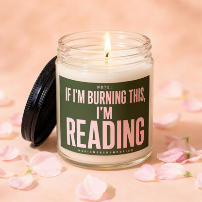 Lit candle with "Note: If I'm burning this, I'm reading" text on label.