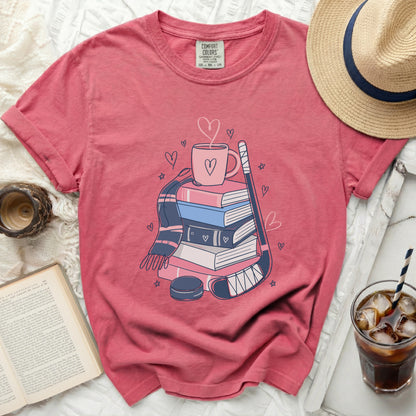Pink t-shirt with books, hockey stick, puck, and hearts graphic.