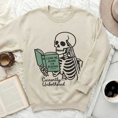Skeleton reading a book with text "Leave Me Alone I'm Reading Currently Unbothered".