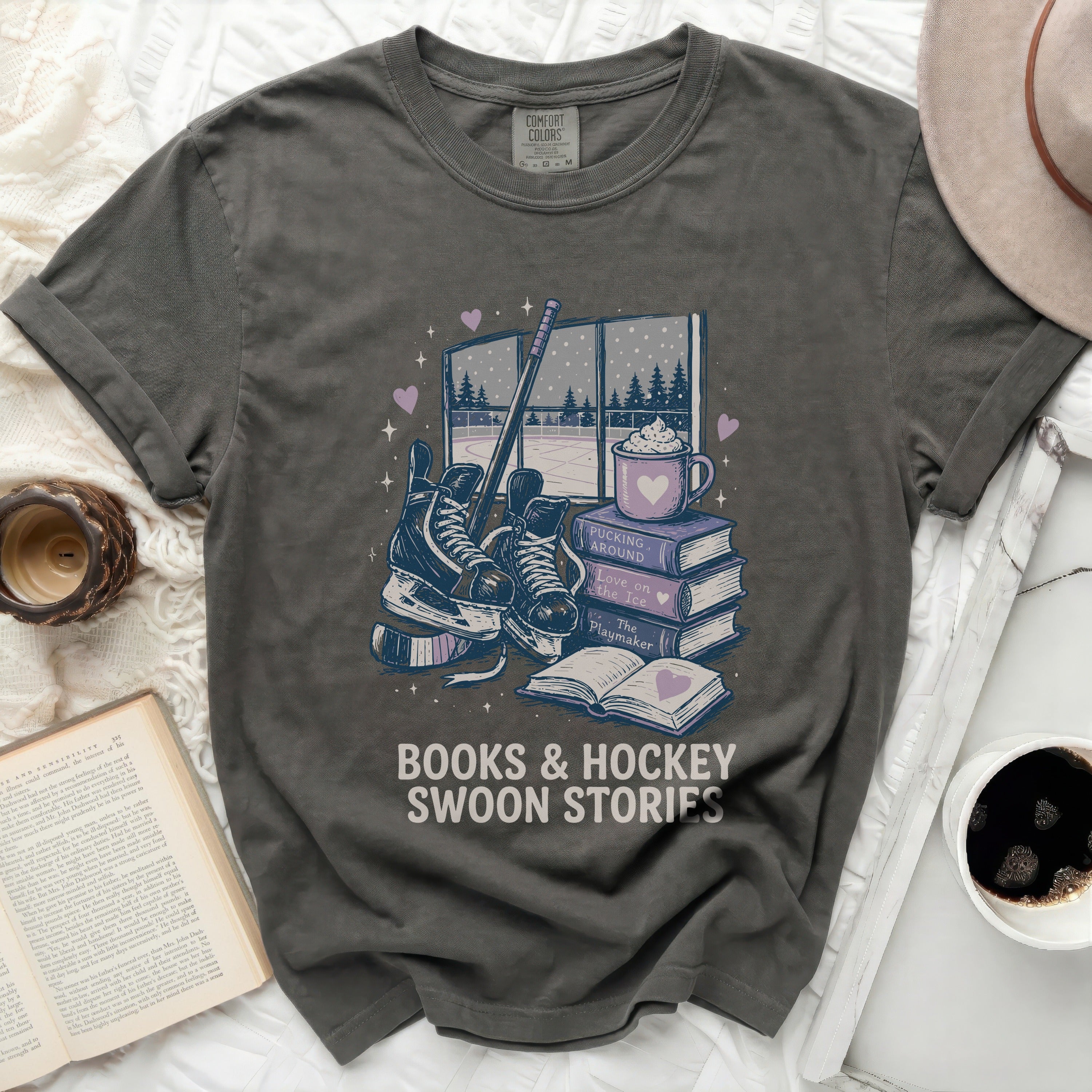 Dark grey t-shirt with books, skates, and hot cocoa graphic and text.
