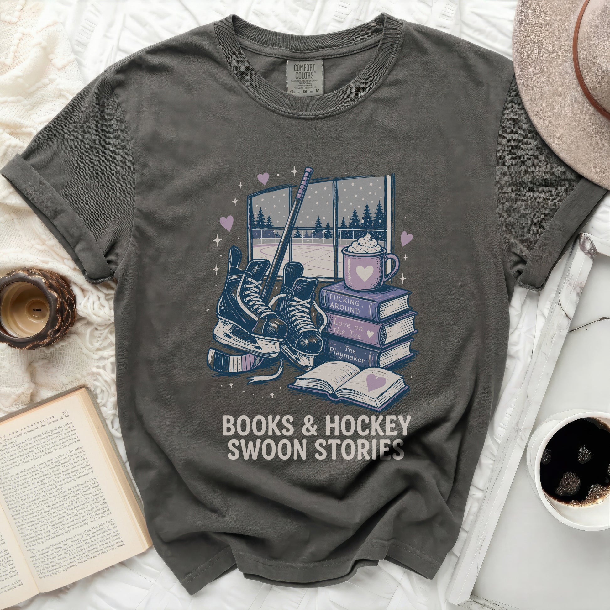 Dark grey t-shirt with books, skates, and hot cocoa graphic and text.