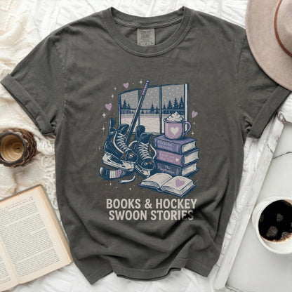 Dark grey t-shirt with books, skates, and hot cocoa graphic and text.