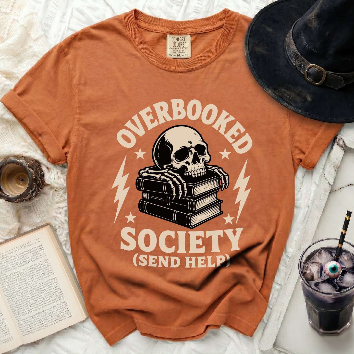 Orange t-shirt with skull on books, text "OVERBOOKED SOCIETY (SEND HELP)".