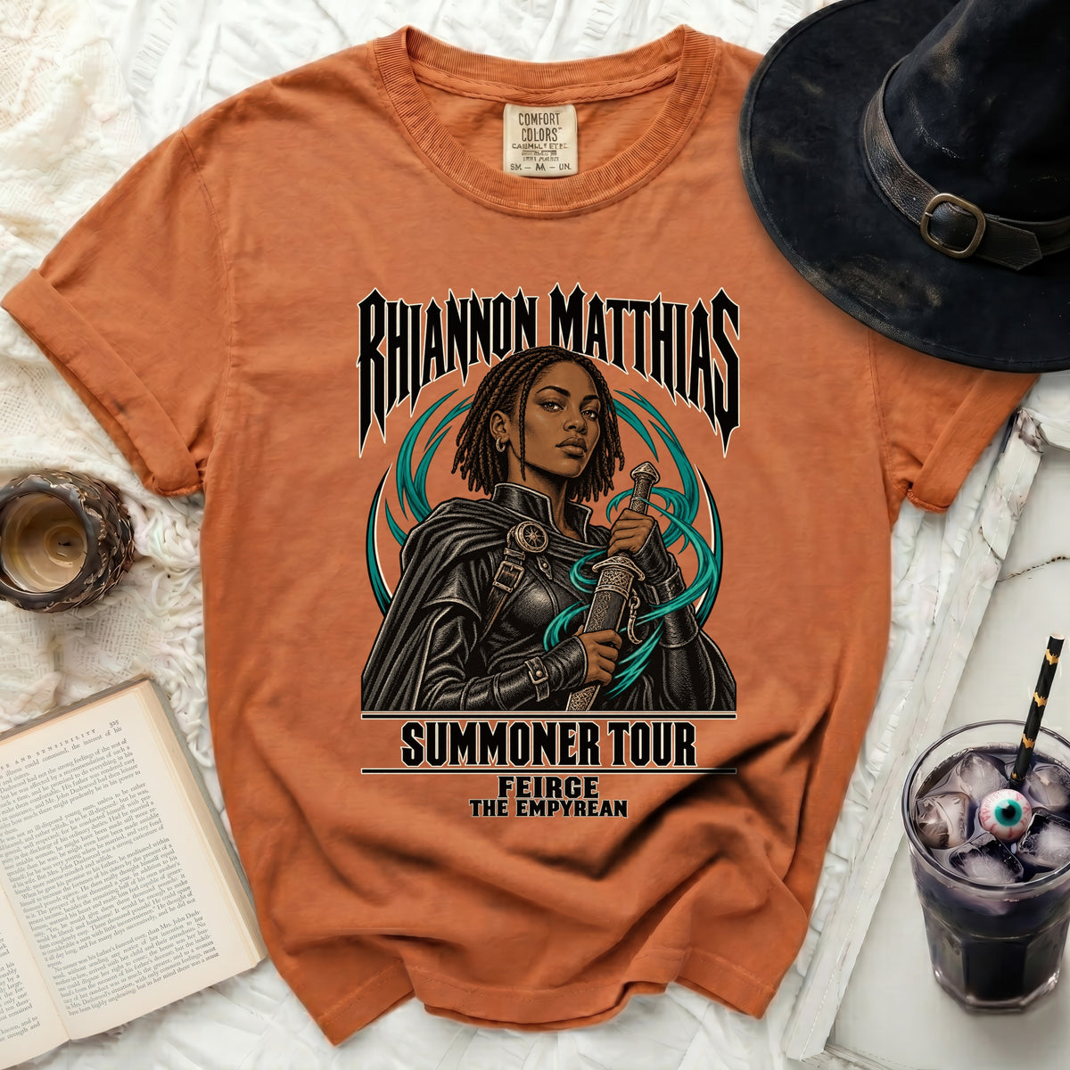 Orange t-shirt with "Rhiannon Matthias Summoner Tour" text and sword-wielding woman graphic.
