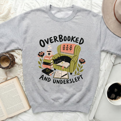 Light gray sweatshirt with "Overbooked and Underslept" graphic of a cat reading in a chair.