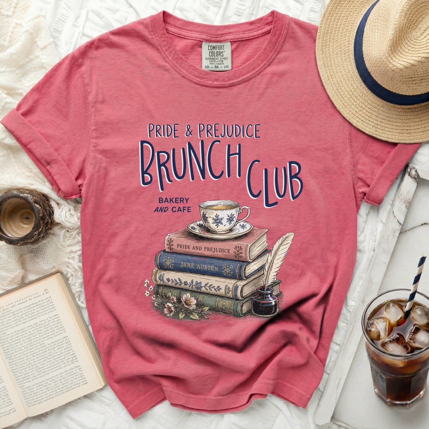 Pink t-shirt with "Pride & Prejudice Brunch Club" graphic and stack of books.