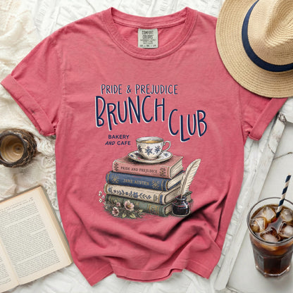 Pink t-shirt with "Pride & Prejudice Brunch Club" graphic and stack of books.