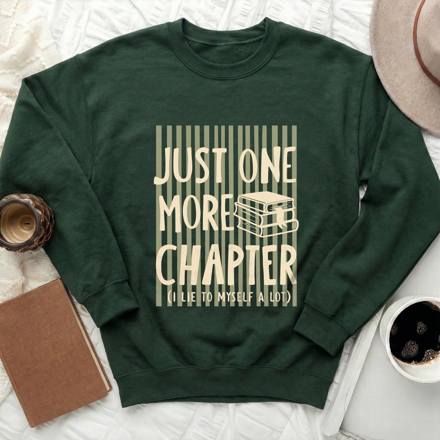 Dark green sweatshirt with "JUST ONE MORE CHAPTER" text and stack of books.