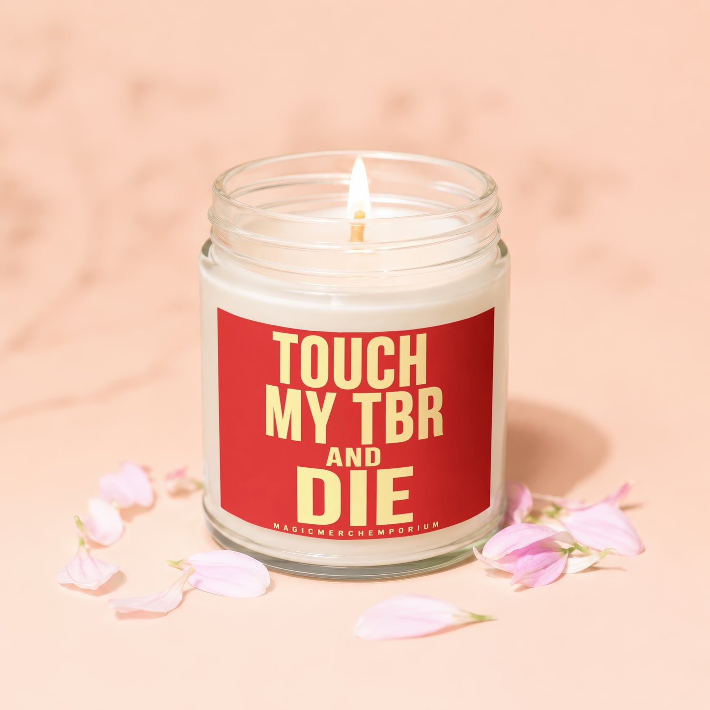 Lit candle in glass jar with red label reading "TOUCH MY TBR AND DIE"