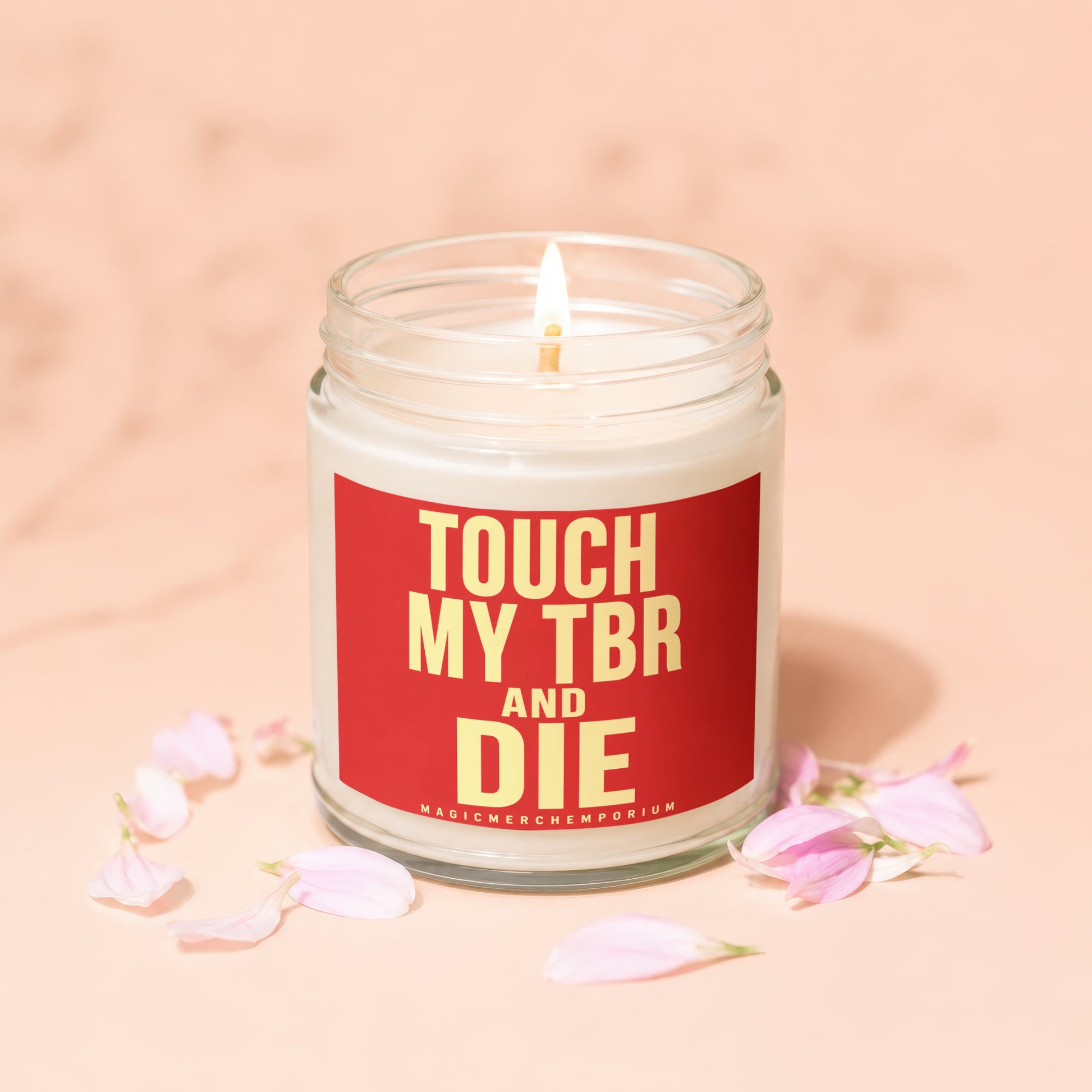 Lit candle in glass jar with red label reading "TOUCH MY TBR AND DIE"