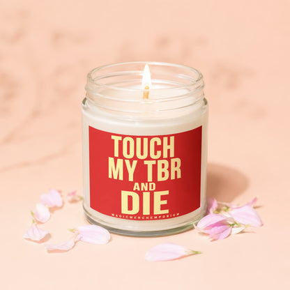 Lit candle in glass jar with red label reading "TOUCH MY TBR AND DIE"