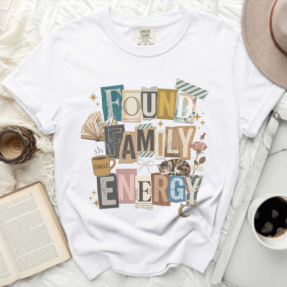 White t-shirt with "Found Family Energy" collage graphic and sleeping cat.