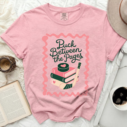 Pink t-shirt with "Puck Between the Pages" text and hockey graphic.