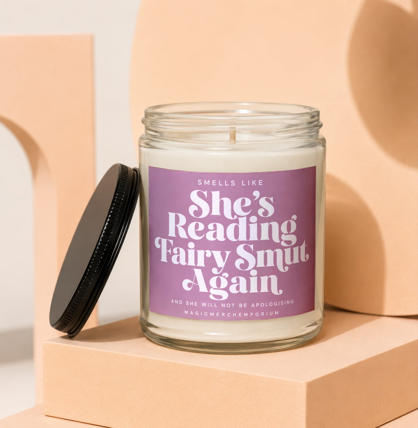 Jar candle with lavender label reading "Smells like she's reading fairy smut again".