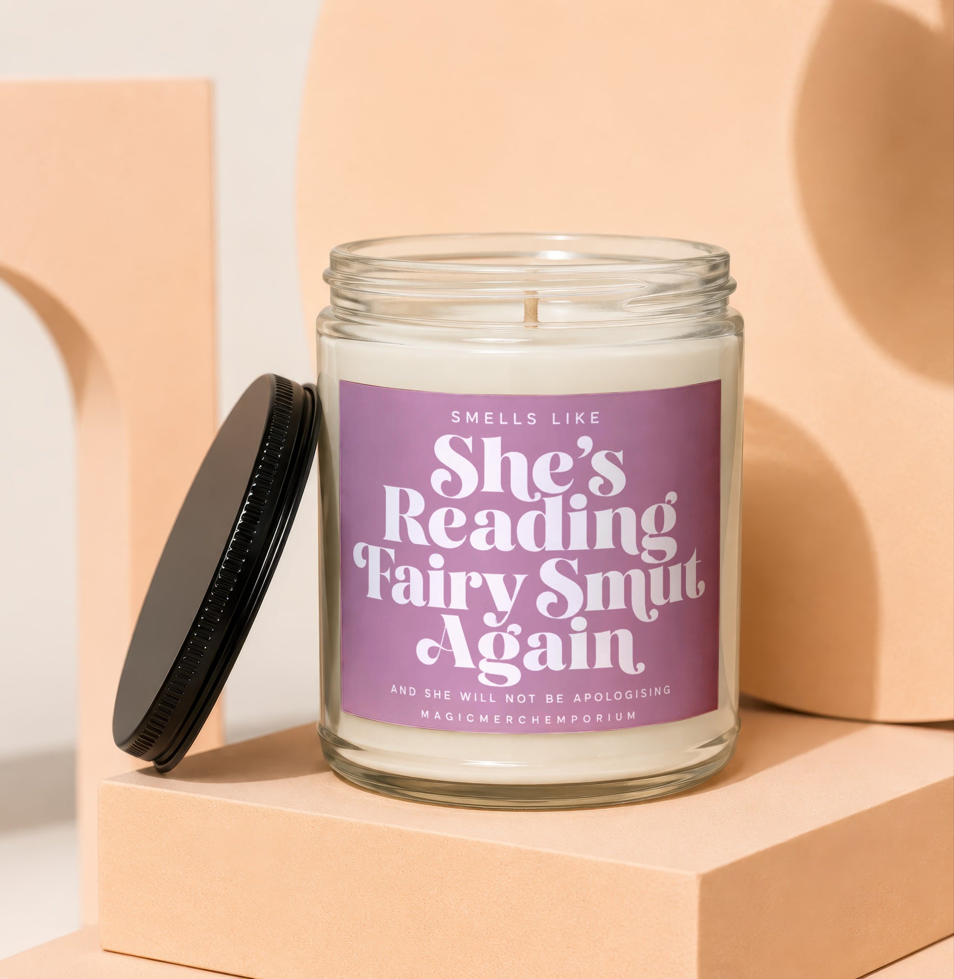 Jar candle with lavender label reading "Smells like she's reading fairy smut again".