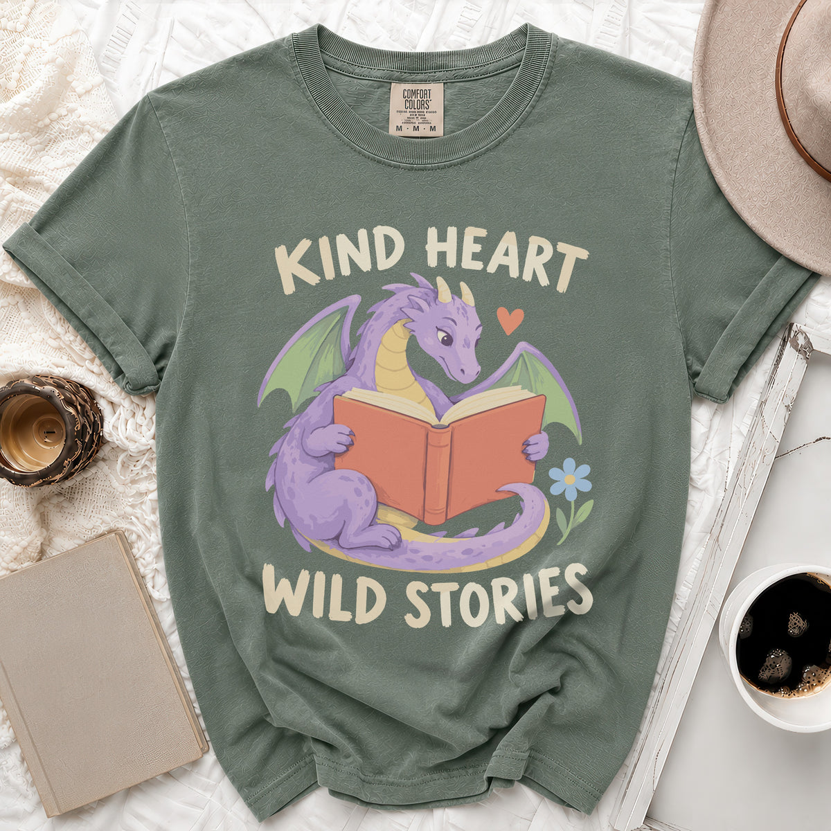 Green t-shirt with purple dragon reading book, text "Kind Heart Wild Stories".