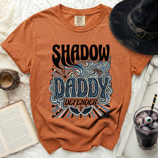 Orange t-shirt with "SHADOW DADDY DEFENDER" text and graphic.