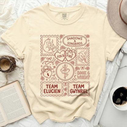 Cream t-shirt with maroon "Shadows & Songbirds", "Fox & Fire", "Team Elucien", and "Team Gwynriel" graphic.