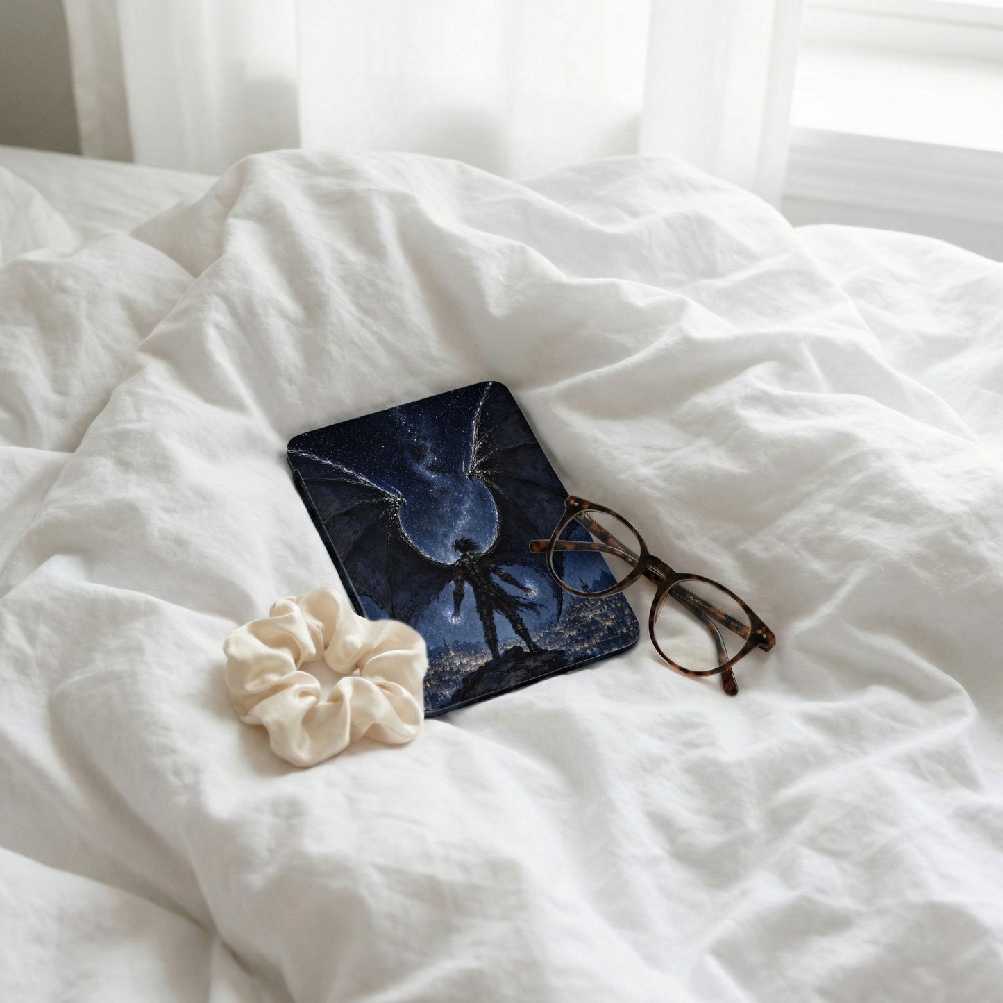 Book with winged figure under starry sky next to glasses and scrunchie.