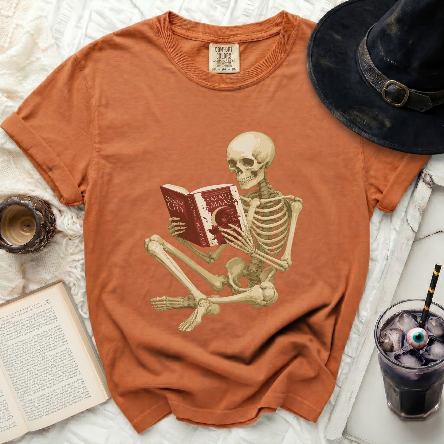 Skeleton reading a book titled "Crescent City" by Sarah J. Maas.