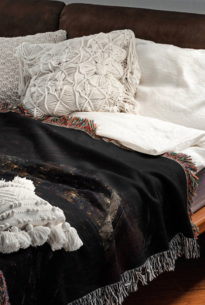 a cozy and inviting bedroom scene, featuring a bed with a black blanket and white pillows, a black and white patterned blanket, and a white throw blanket.