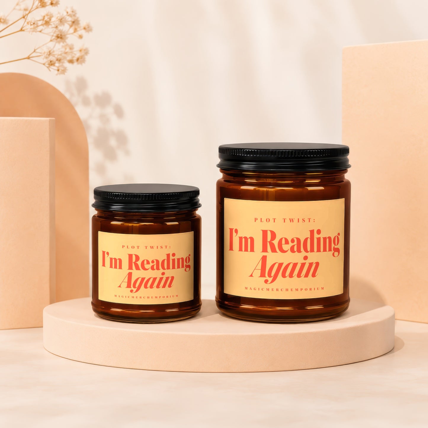Two amber glass candles with black lids and yellow labels that say "I'm Reading Again".