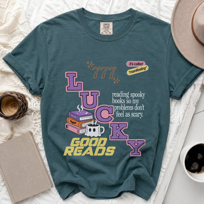 Teal t-shirt with "LUCKY" spelled out, spooky books, ghost mug, and text.