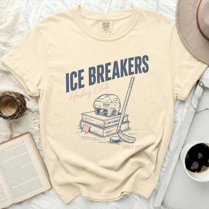 "ICE BREAKERS Hockey Club" text on a cream t-shirt with hockey stick and books.