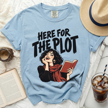 Light blue t-shirt with "Here for the Plot" text and illustrated woman reading.