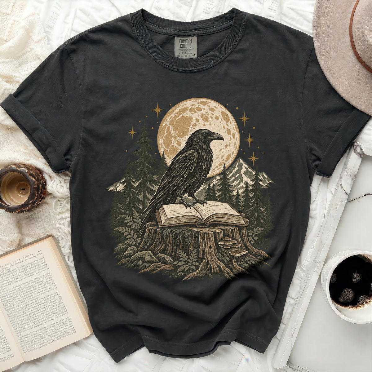 Black t-shirt with raven on open book under moon and stars.
