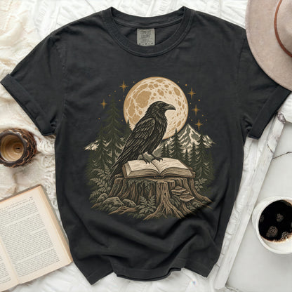 Black t-shirt with raven on open book under moon and stars.