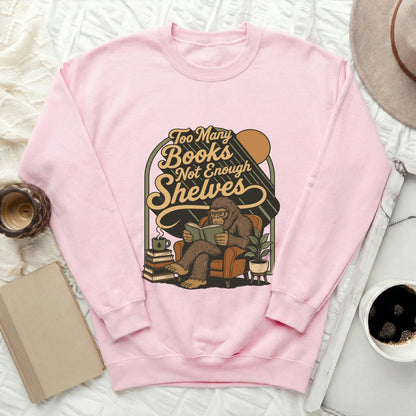 Pink sweatshirt with Bigfoot reading a book and text "Too Many Books Not Enough Shelves".
