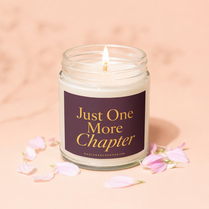 Glass candle with lit wick and label that reads "Just One More Chapter".